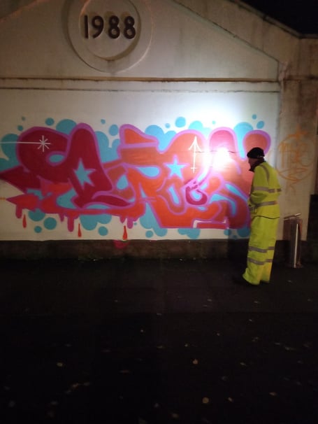 A worker cleans up the graffiti at the bus station