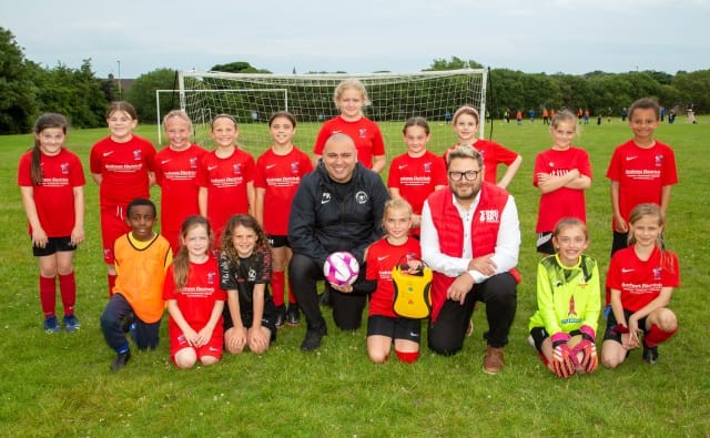 Red Sky Foundation's Sergio Petrucci, Co-founder, and Team Grassroots Founder Paul Kirton join Luna, the daughter of the foundation founder and teammates at the famous Boldon Girls FC in South