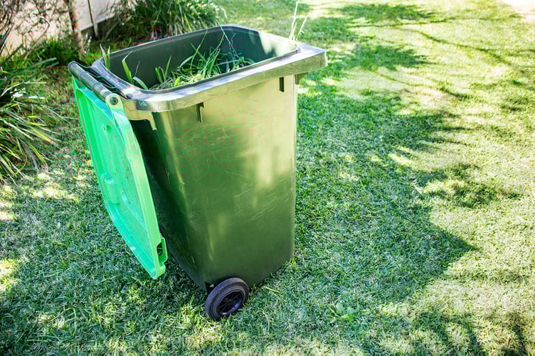 Green bin container filled with garden waste. Spring clean up in the garden. Council bin collection. Recycling garbage for a better environment.