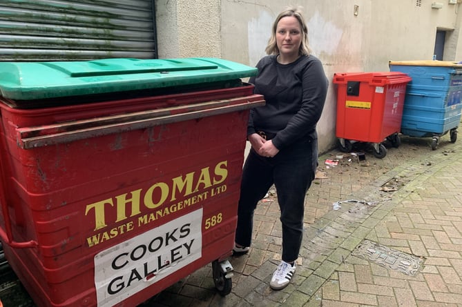 An angry lady standing next to a bin