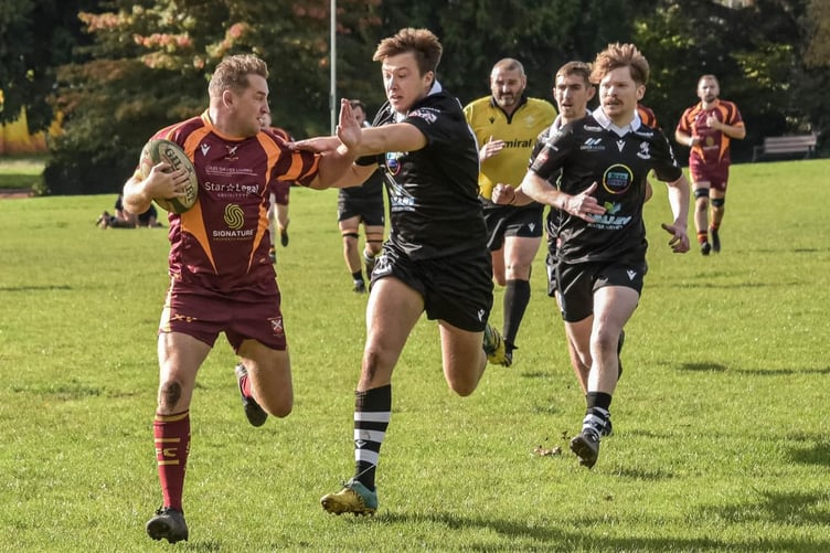 A Quins player holds off a Nomad in the race for the line