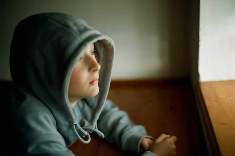 Stock photo of child with hood up, looking pensive. Mental health in children and young people
