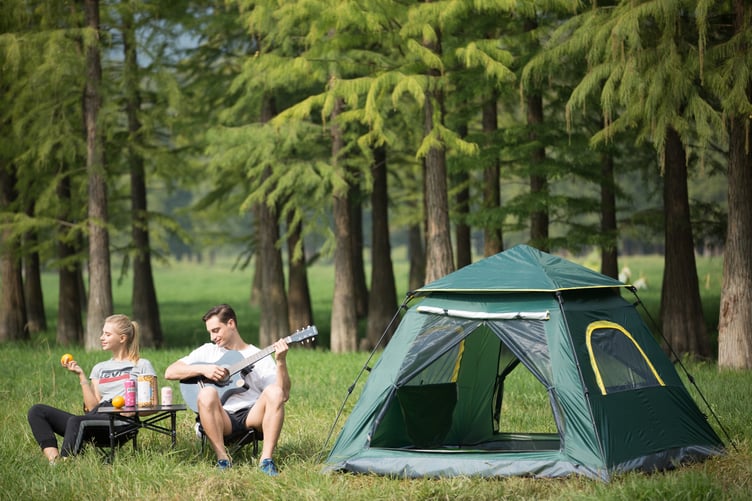 Man playing a guitar outside a tent
